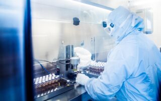 Fully gowned laboratory scientist capping vials during monoclonal antibody manufacturing